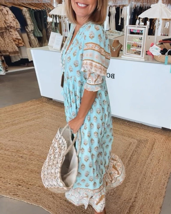 Woman in a light blue dress with a pattern, holding a large white handbag with decorative elements, standing in a store.
