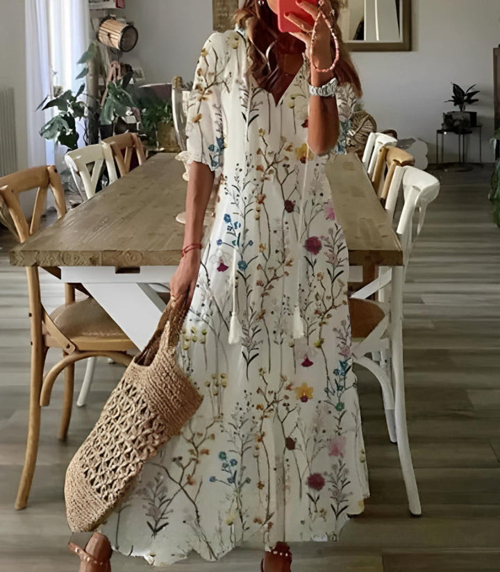 Woman in a floral dress holding a woven bag in a dining room.