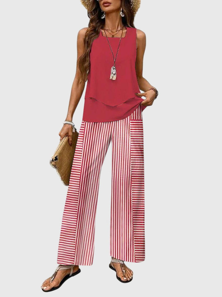 Woman wearing a red sleeveless top and red and white striped pants on a light gray background