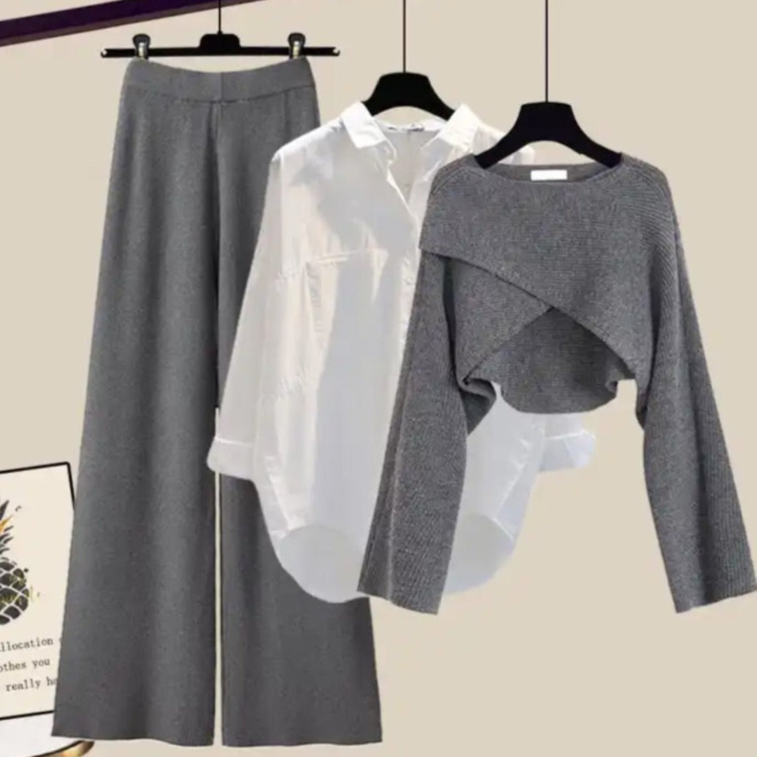 Gray skirt, white shirt, and gray sweater on hangers against a beige background