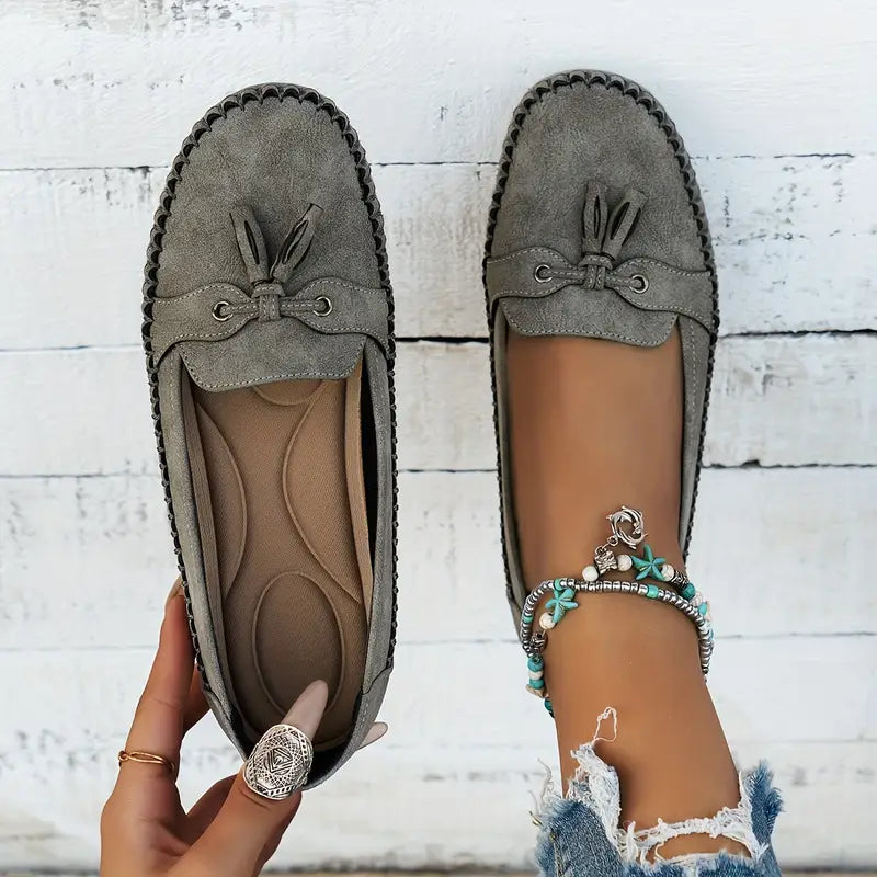 Gray loafers with tassels on a white wooden background