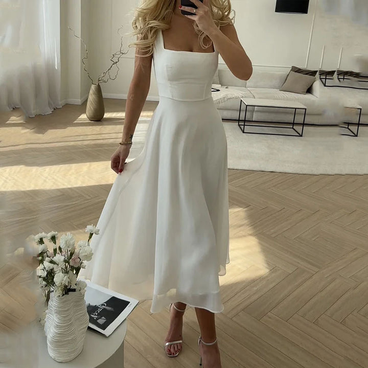 Woman in a white dress standing in a modern living room.