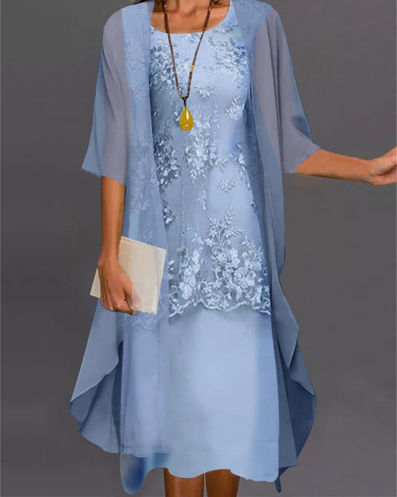 Woman wearing a light blue lace dress with a matching cardigan against a gray background