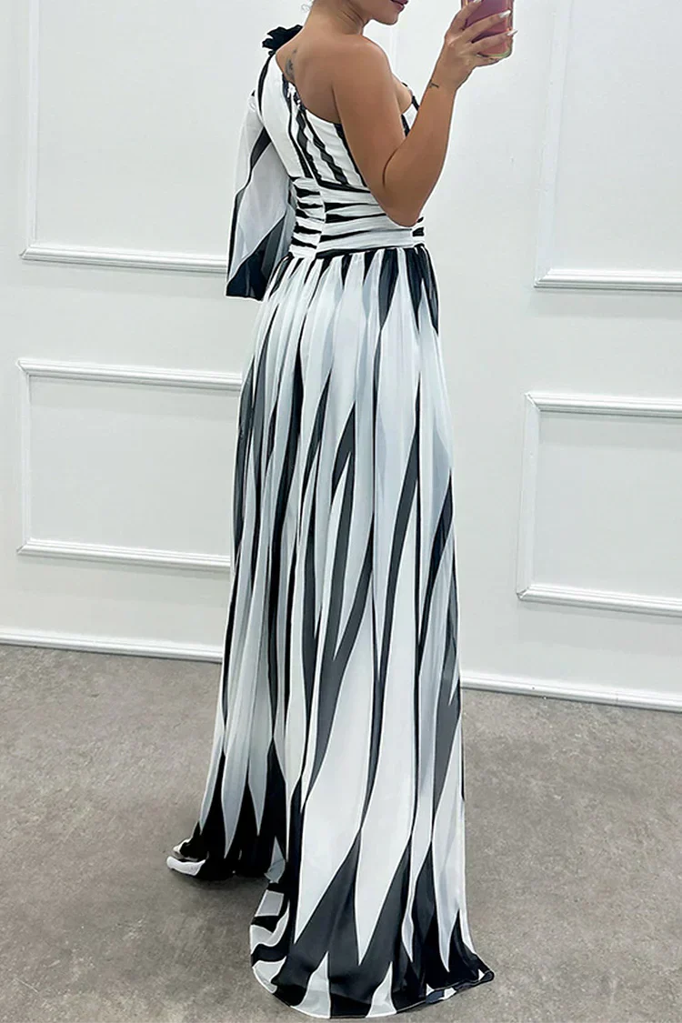Woman wearing a black and white striped dress against a white wall.