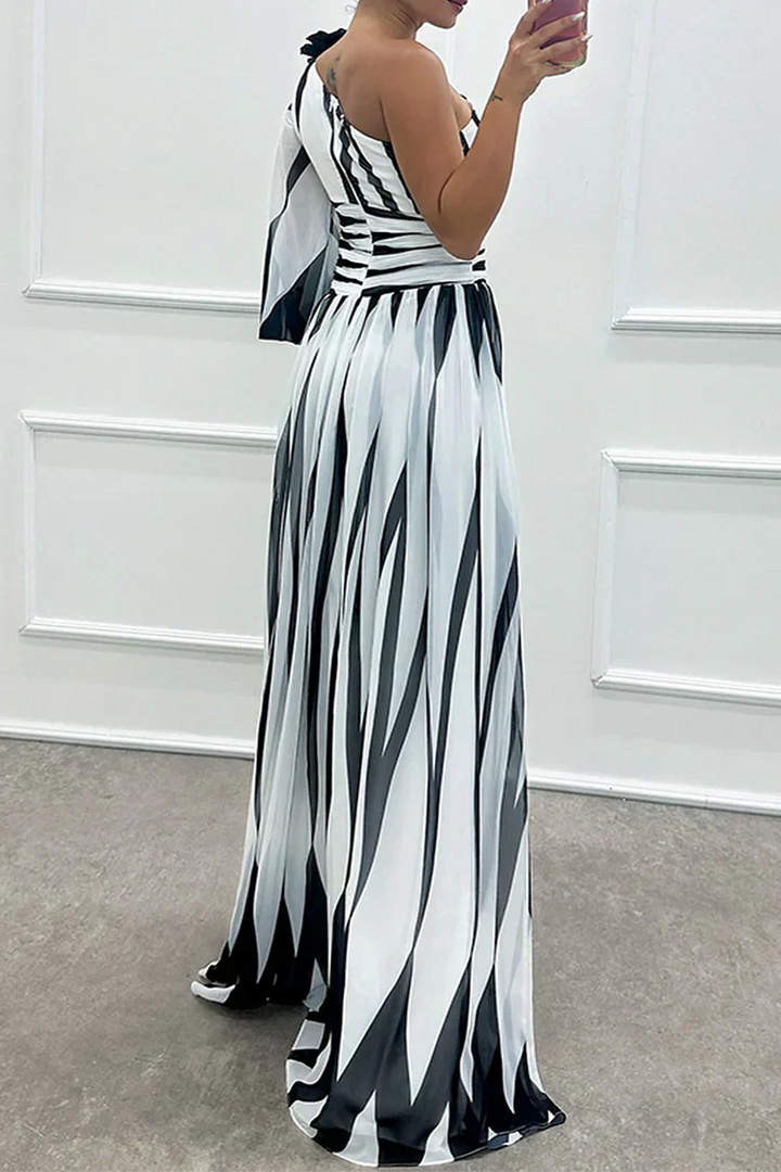 Woman wearing a black and white striped dress against a white wall.