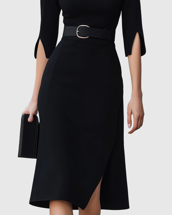 Black dress with a belt and a hand holding a clutch on a white background