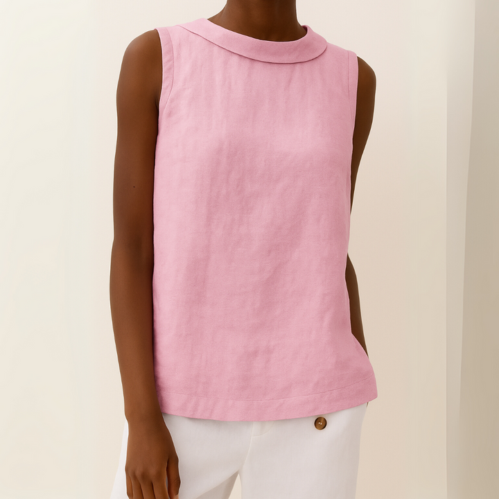 Person wearing a pink sleeveless top with a collar against a beige background