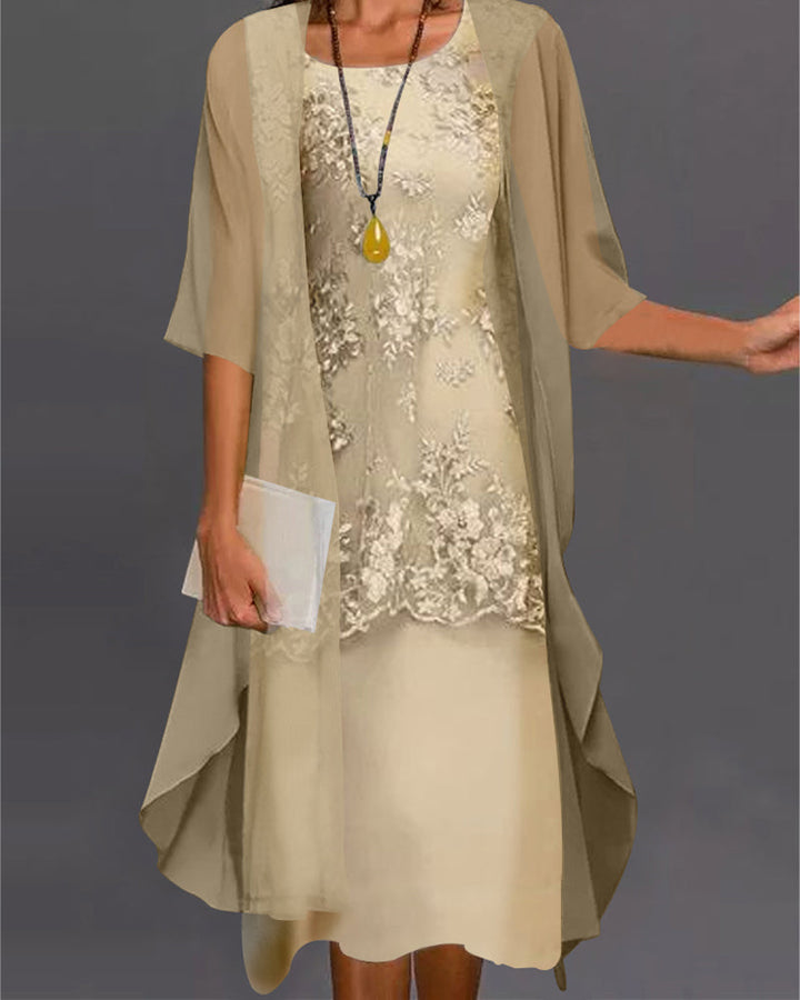 Woman wearing a beige dress with floral embellishments and a matching cardigan against a gray background