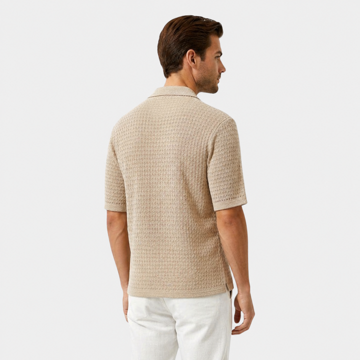 Man wearing a beige textured shirt and white pants on a light gray background