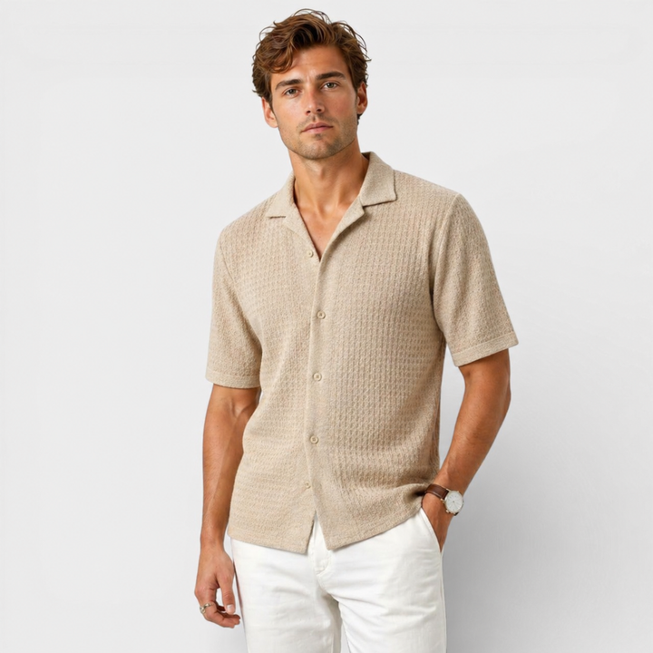 Man wearing a beige textured shirt and white pants on a light gray background