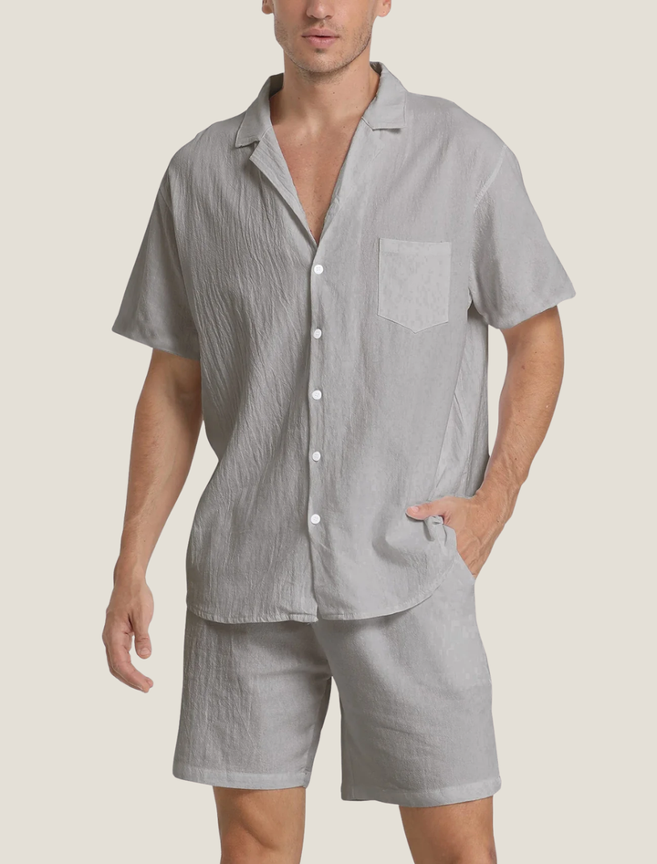 Man wearing a gray short-sleeve shirt and shorts set on a beige background