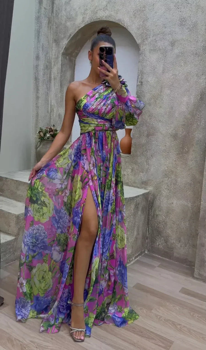 Woman taking a mirror selfie wearing a colorful floral dress in an indoor setting.