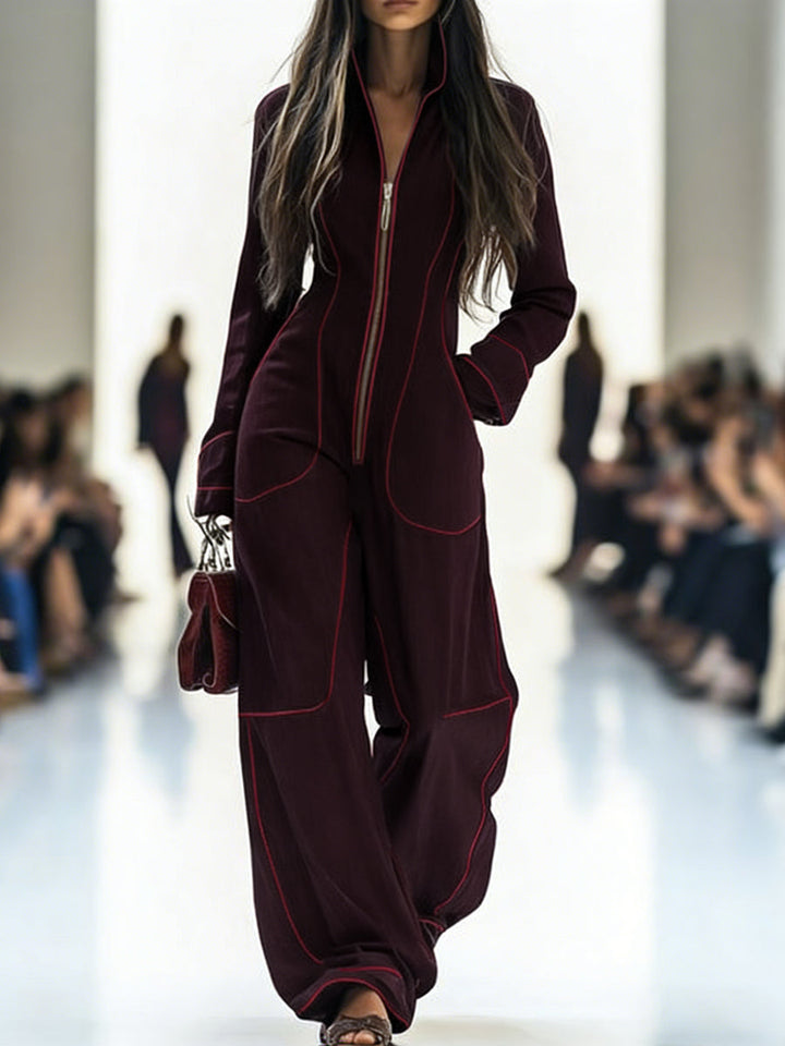 Model wearing a burgundy outfit with red piping on a runway.