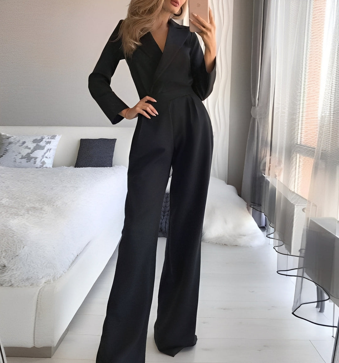 Person wearing a black jumpsuit in a modern bedroom.