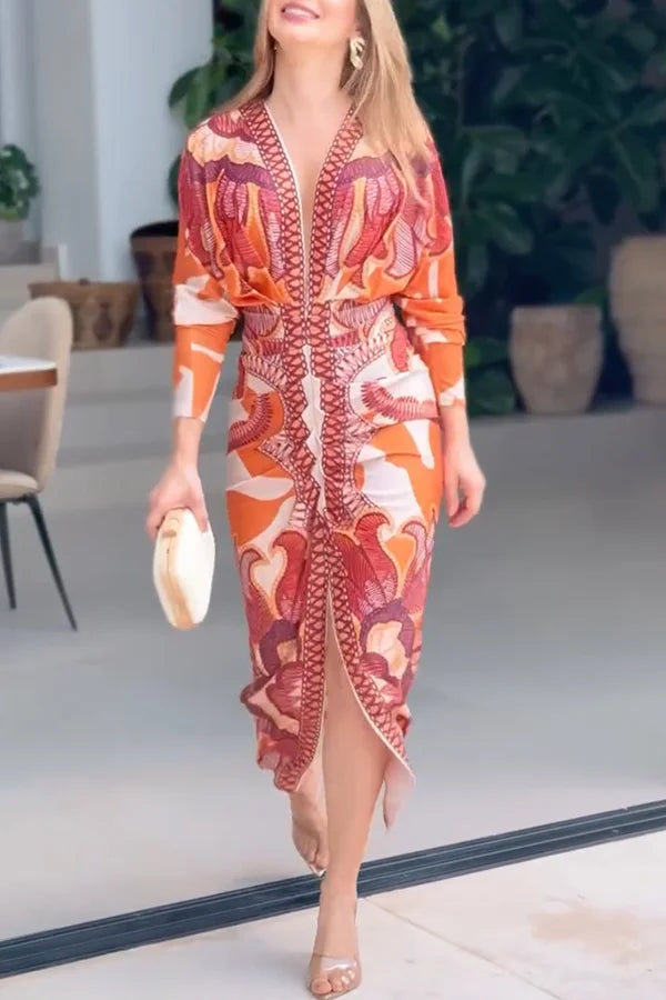 Woman wearing a patterned orange dress in an indoor setting with plants in the background