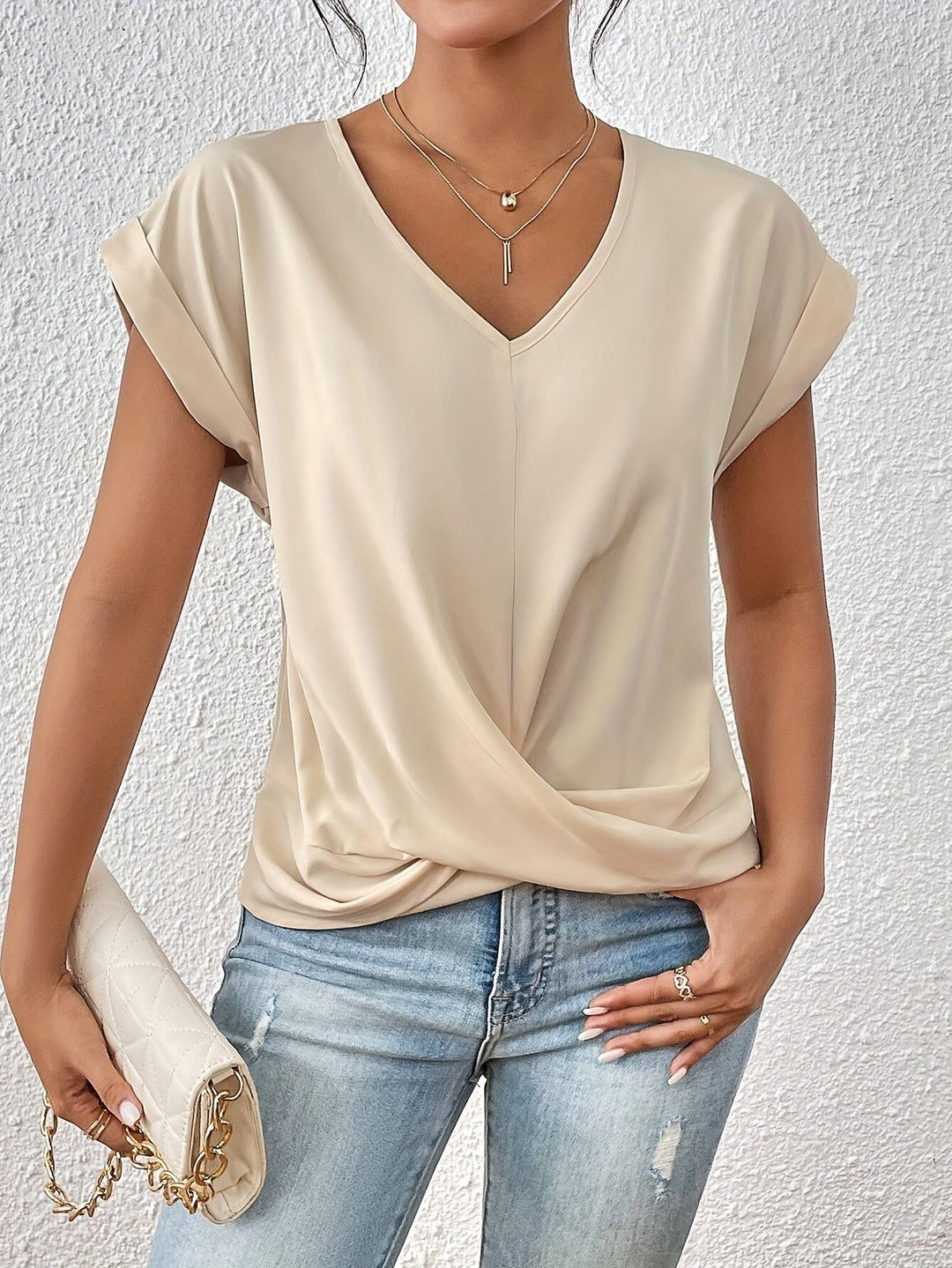 Woman wearing a beige top and blue jeans against a white background