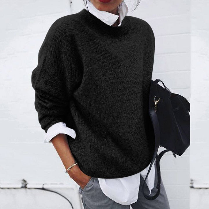 Person wearing a black sweater over a white shirt with a black backpack against a white background