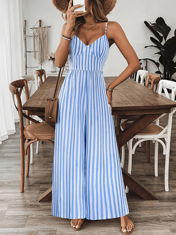 Woman in a blue and white striped dress standing in a room with wooden furniture.