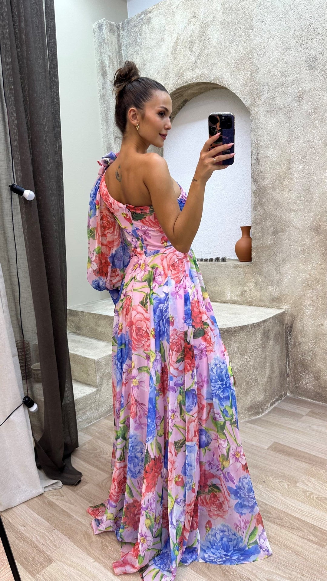 Woman in a colorful floral dress taking a mirror selfie.