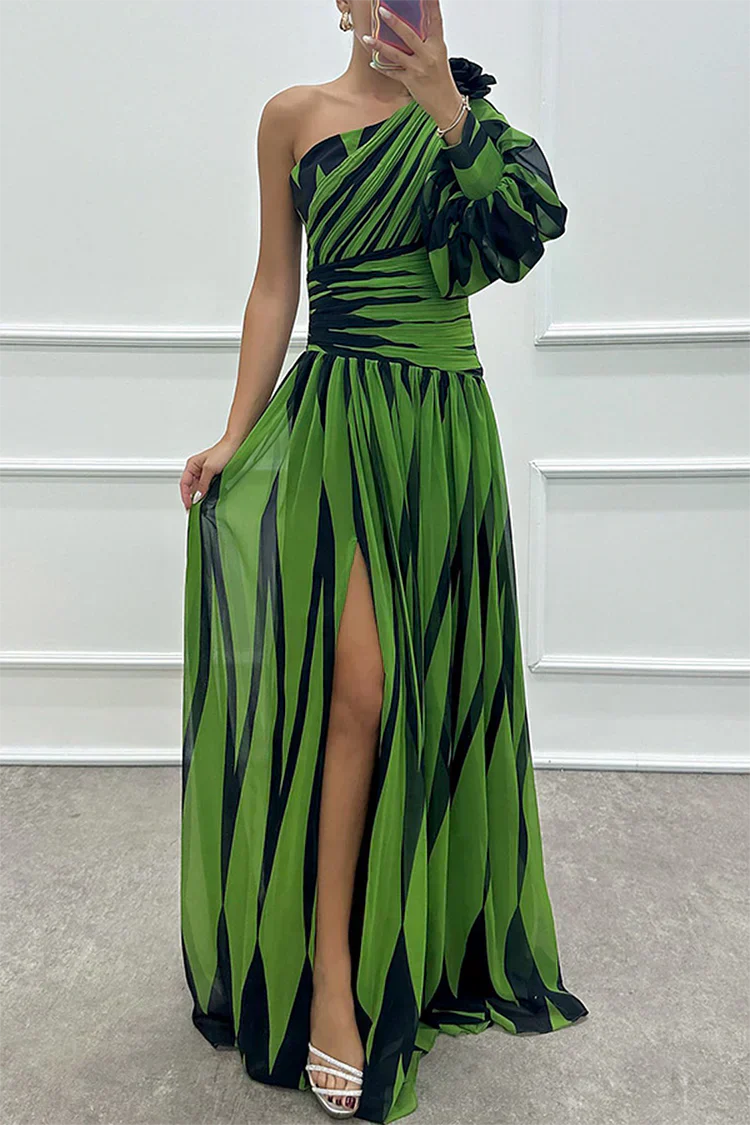 Green and black patterned one-shoulder dress with a slit on a plain background