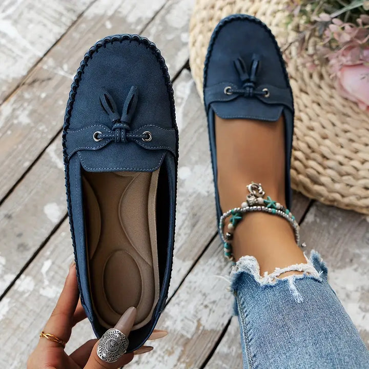 Blue loafers with tassels on a wooden floor