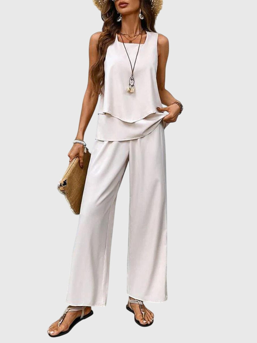 Woman wearing a white sleeveless top and wide-leg pants on a light gray background