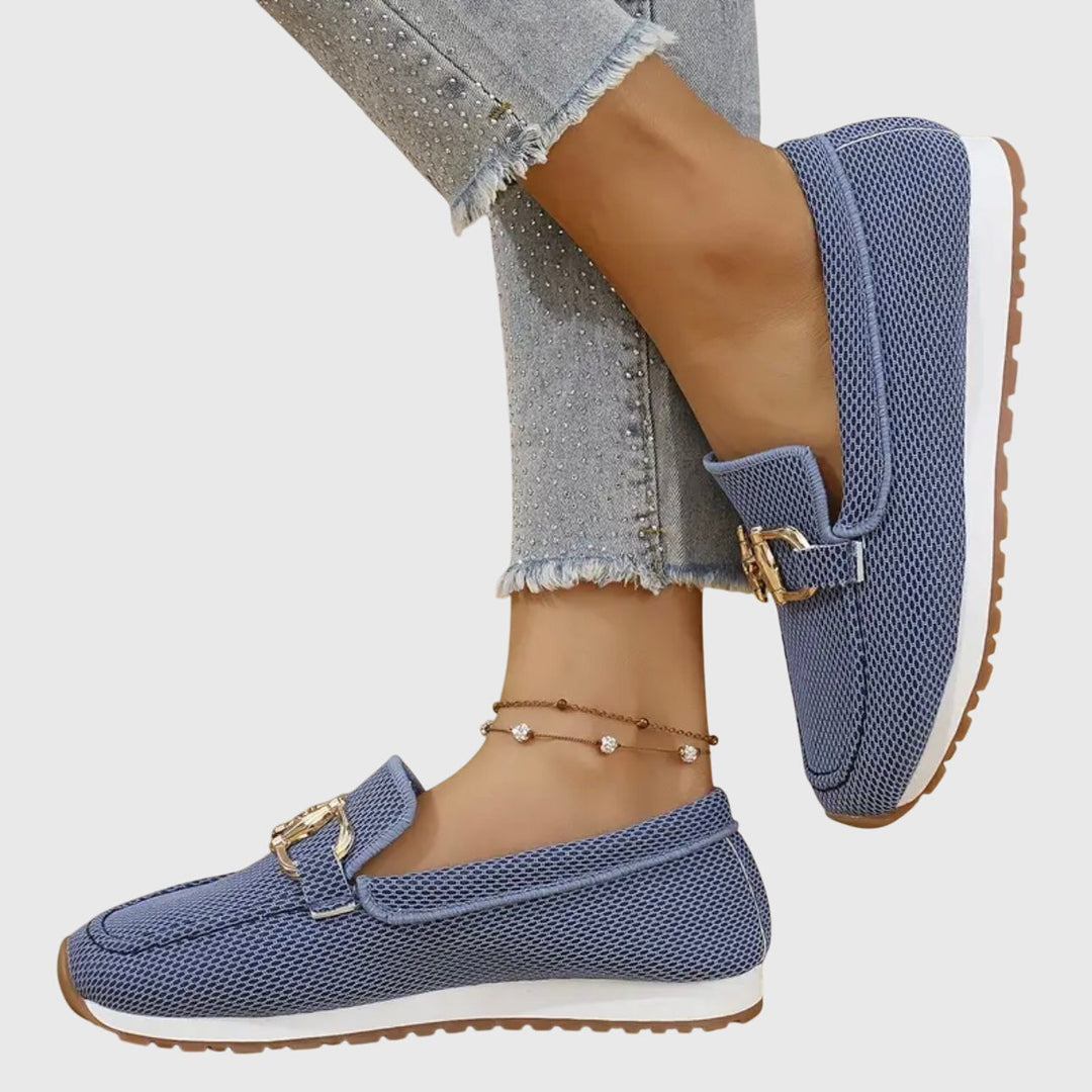 Blue loafers worn with light blue jeans on a white background