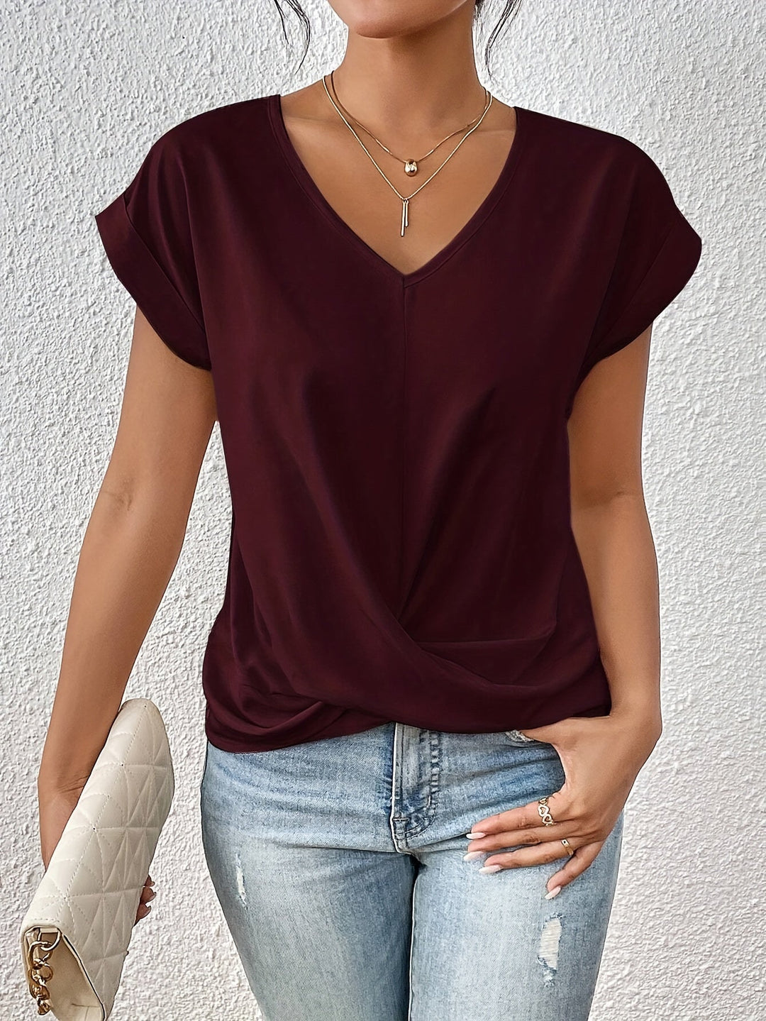 Person wearing a burgundy top and light blue jeans against a white background