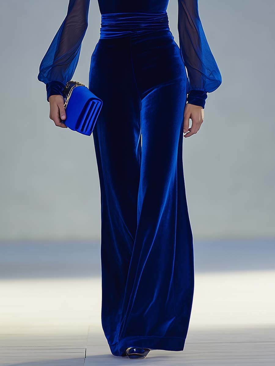 Blue velvet evening gown with sheer sleeves on a neutral background