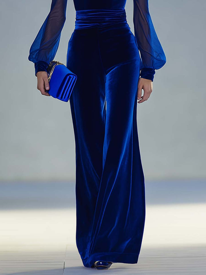 Blue velvet evening gown with sheer sleeves on a neutral background