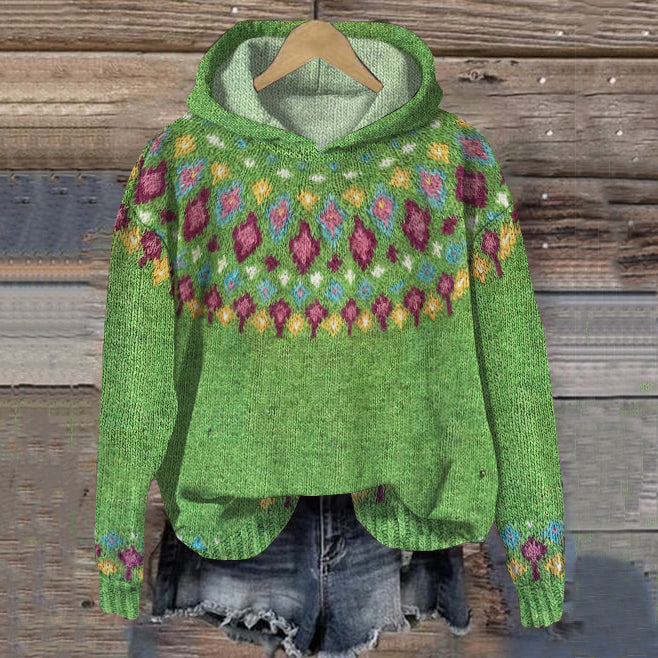 Green knitted sweater with colorful pattern on a wooden background
