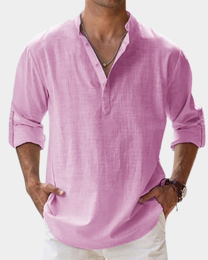Man wearing a pink long-sleeve shirt with rolled-up sleeves on a white background