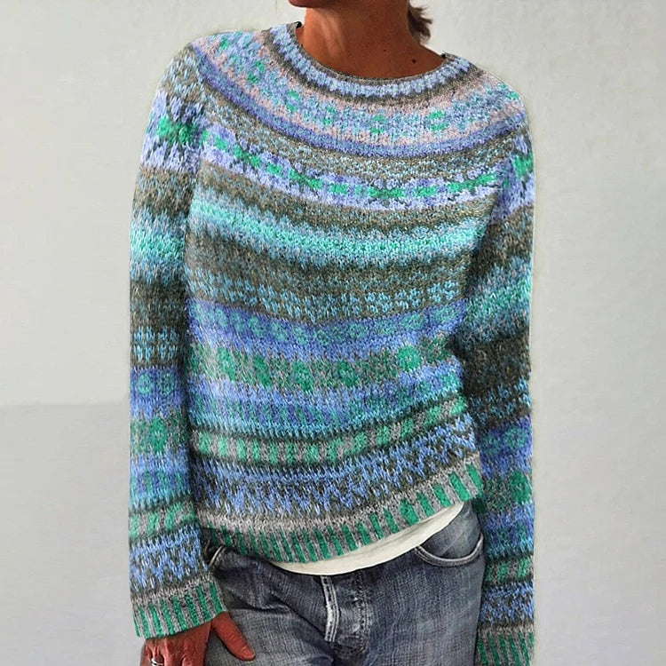 Person wearing a multicolored patterned sweater on a plain background