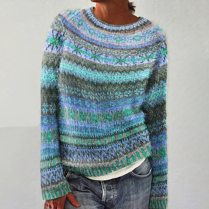 Person wearing a multicolored patterned sweater on a plain background