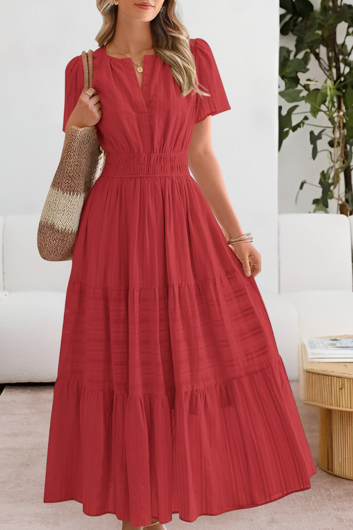 Woman wearing a red dress holding a textured bag indoors.