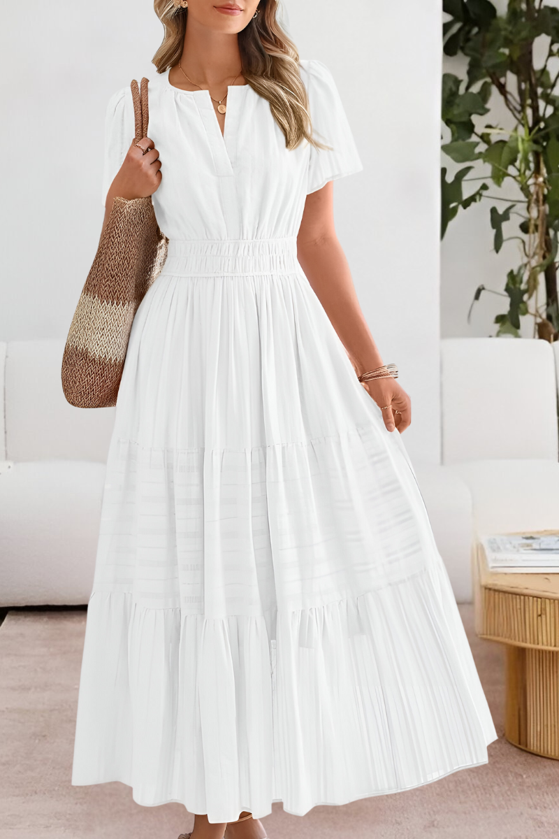 Woman wearing a white dress in a room with a couch and plant