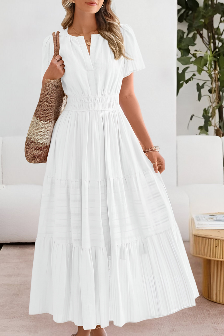 Woman wearing a white dress in a room with a couch and plant