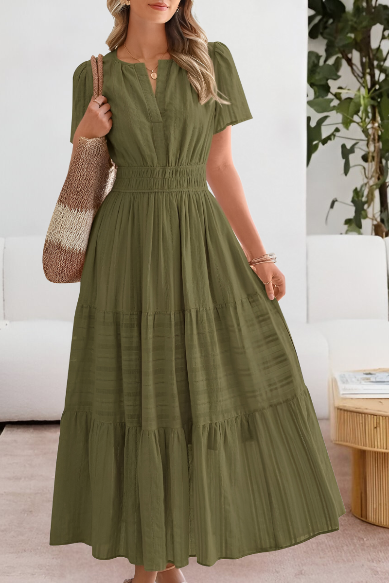Woman wearing a green dress in a room with a white couch and plant.