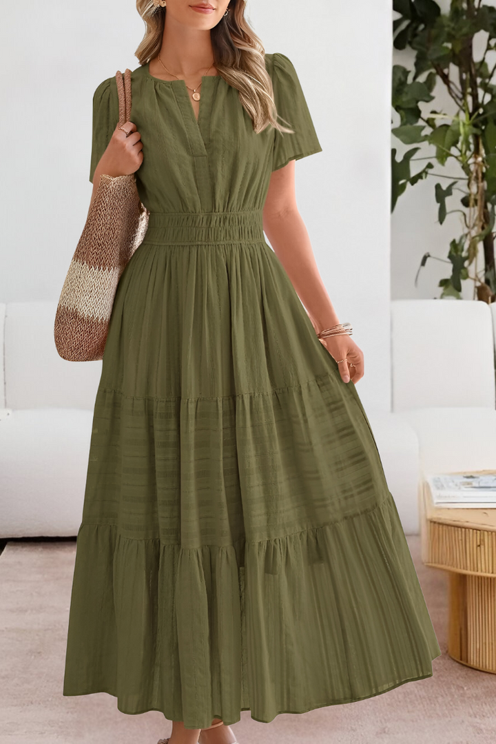 Woman wearing a green dress in a room with a white couch and plant.