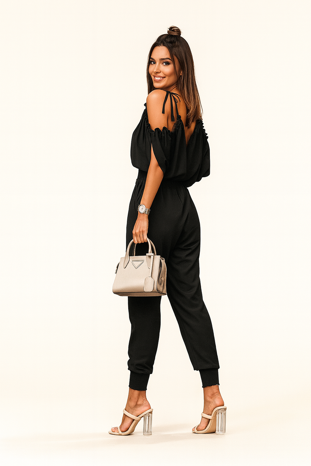Woman in a black outfit holding a beige handbag on a white background