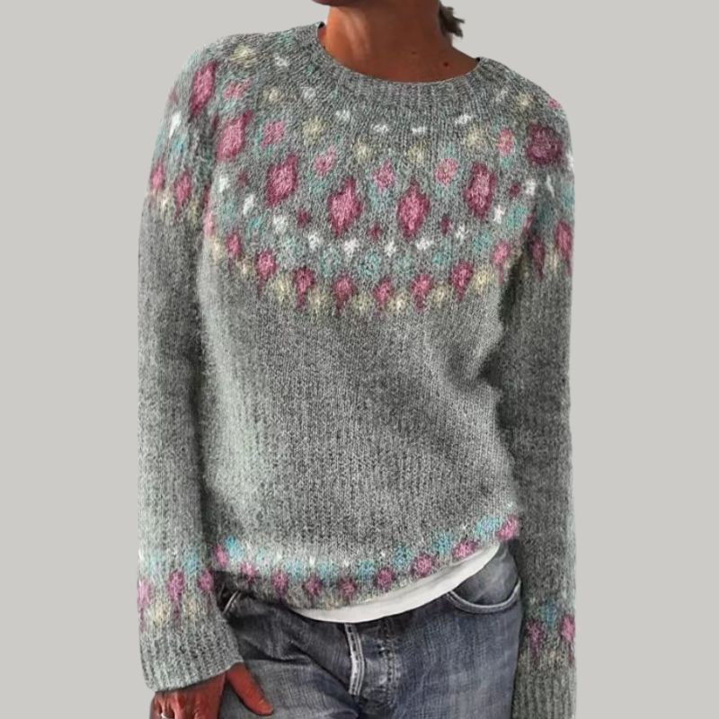 Person wearing a gray sweater with a colorful pattern on a plain background