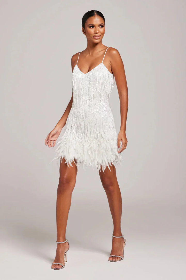 Woman wearing a white fringe dress on a plain background