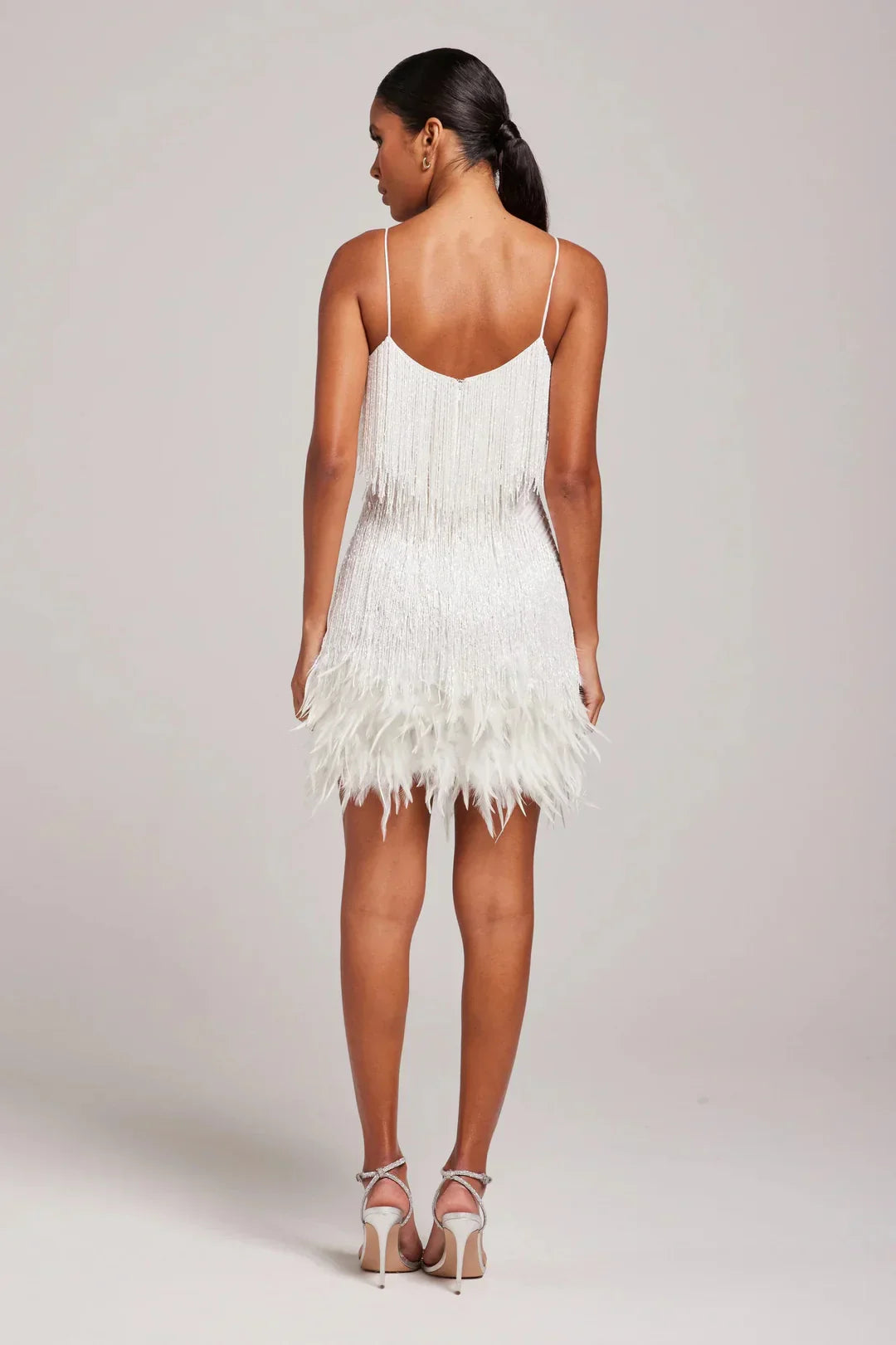 Woman wearing a white feathered dress on a plain background
