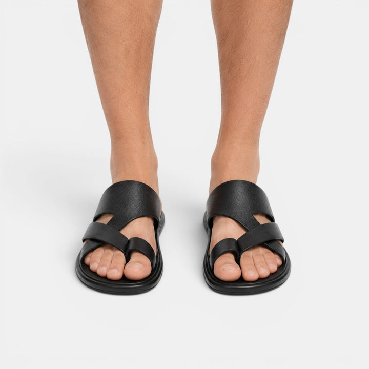 Black sandals worn by a person on a white background
