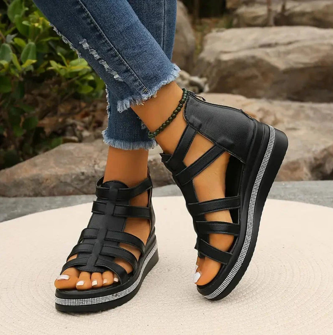 Black platform sandals worn with ripped jeans against a natural background