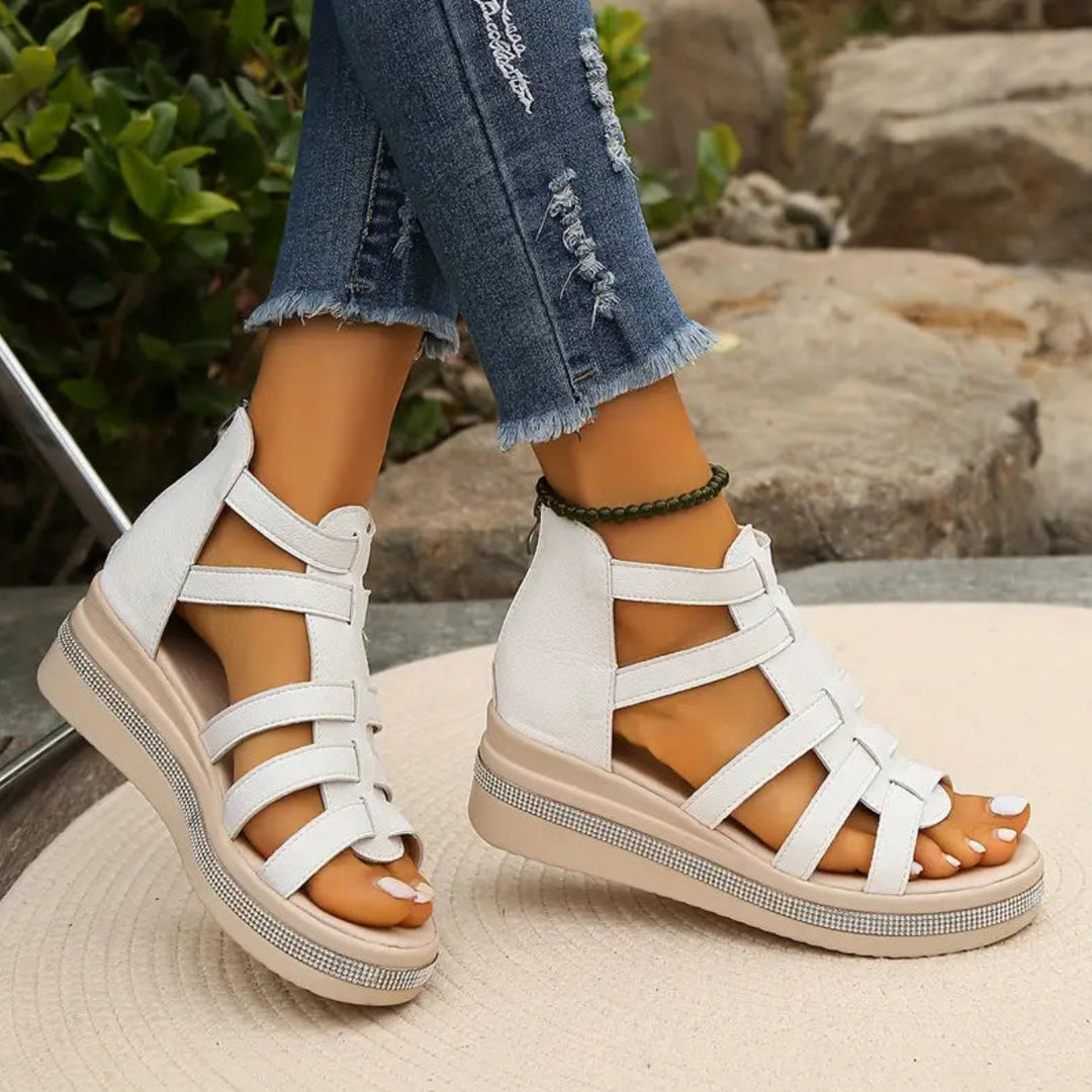 White sandals with brown soles worn with ripped jeans on a natural background