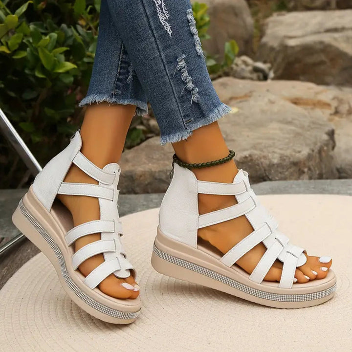 White sandals with brown soles worn with ripped jeans on a natural background