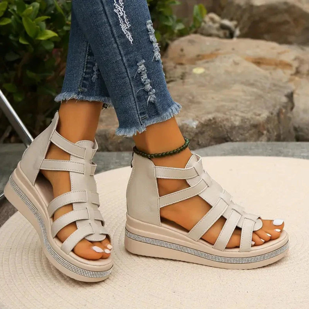 Beige sandals worn with ripped jeans against a natural background