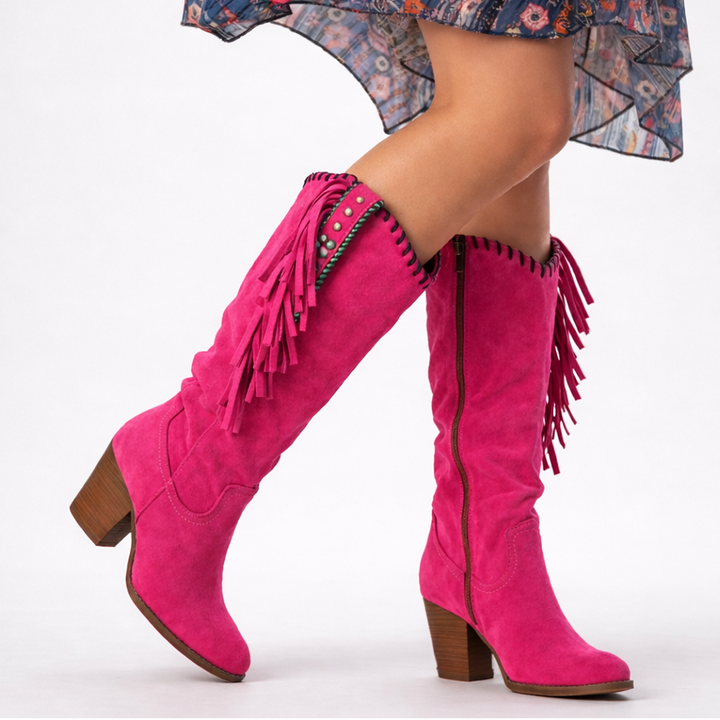 Pink suede boots with fringe details on a white background
