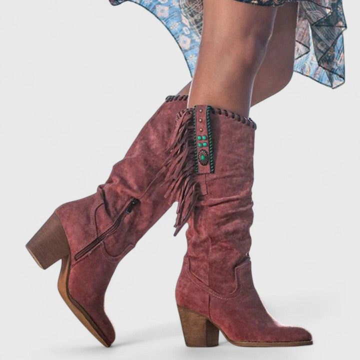 Red suede boots with fringe details on a white background